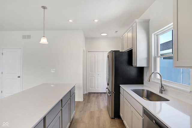 kitchen with decorative light fixtures, a healthy amount of sunlight, light wood-type flooring, and sink