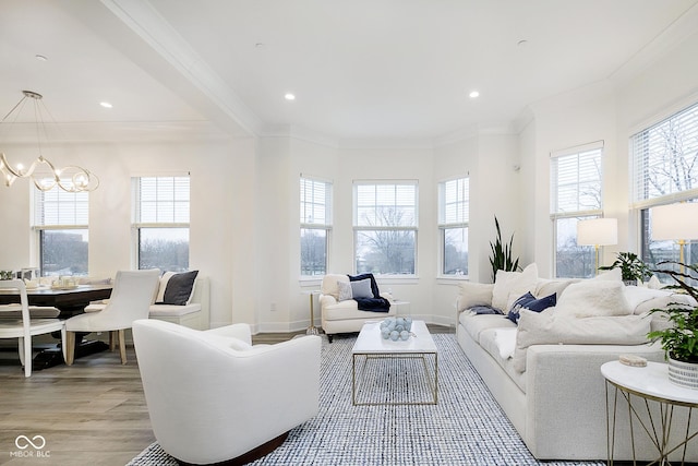 living room featuring a chandelier, light wood-type flooring, and crown molding