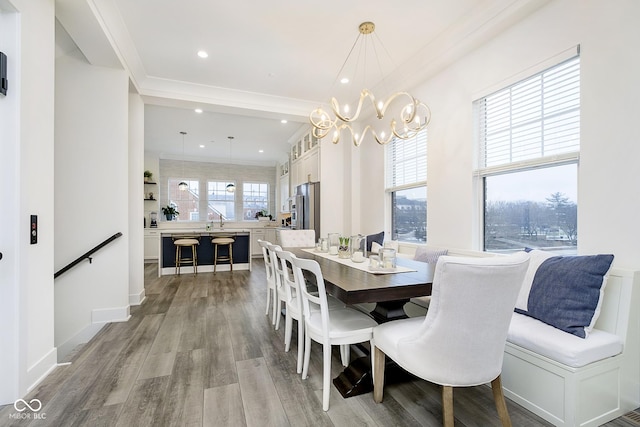 dining area featuring light hardwood / wood-style floors, ornamental molding, and an inviting chandelier