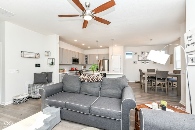 living room with ceiling fan and light hardwood / wood-style flooring