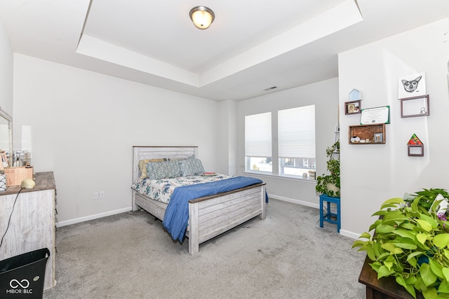 bedroom with light carpet and a raised ceiling