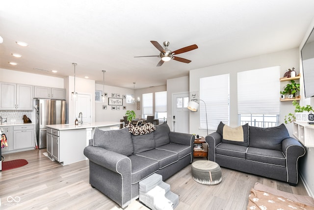 living room featuring ceiling fan, light wood-type flooring, and sink