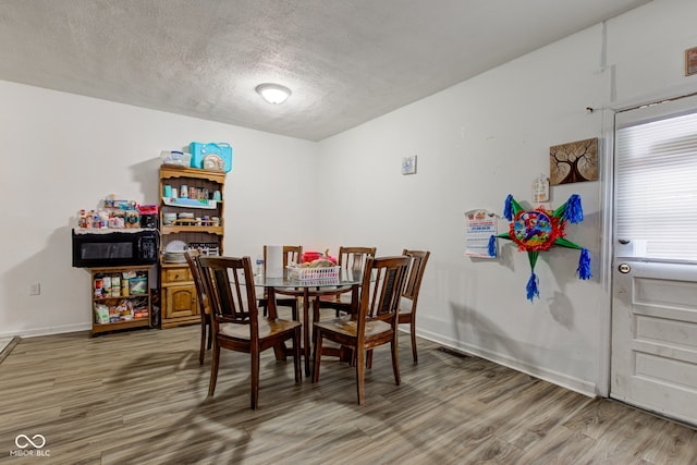 dining area with hardwood / wood-style flooring and a textured ceiling