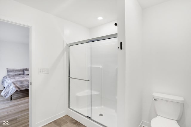 bathroom featuring toilet and a shower with shower door