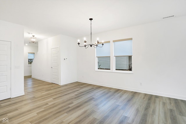 spare room with a chandelier and light hardwood / wood-style floors