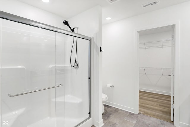 bathroom featuring toilet and a shower with shower door