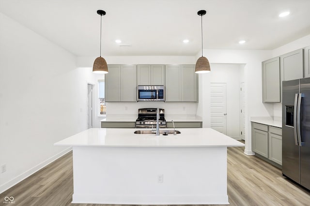 kitchen featuring stainless steel appliances, gray cabinets, and an island with sink