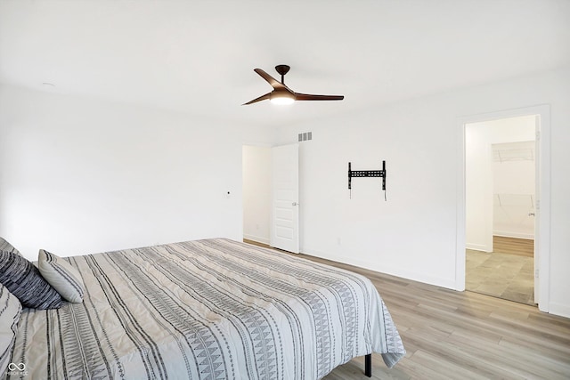 bedroom with ceiling fan, a walk in closet, a closet, and hardwood / wood-style flooring