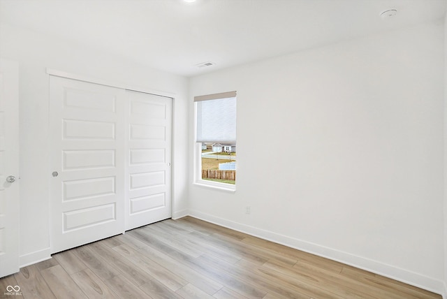 unfurnished bedroom with light wood-type flooring and a closet