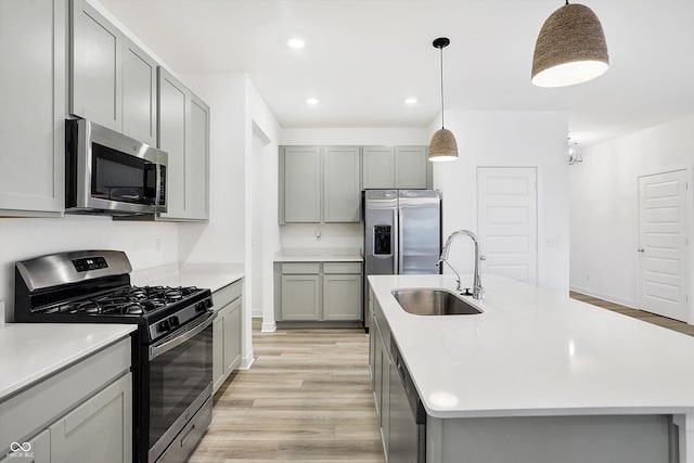 kitchen featuring sink, a kitchen island with sink, gray cabinetry, and appliances with stainless steel finishes