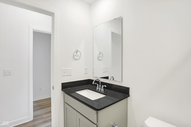 bathroom with toilet, vanity, and hardwood / wood-style flooring