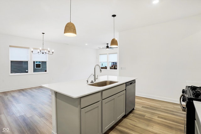 kitchen featuring gas range, dishwasher, a kitchen island with sink, gray cabinets, and sink