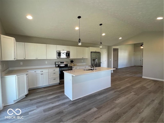 kitchen featuring white cabinets, pendant lighting, stainless steel appliances, and a center island with sink