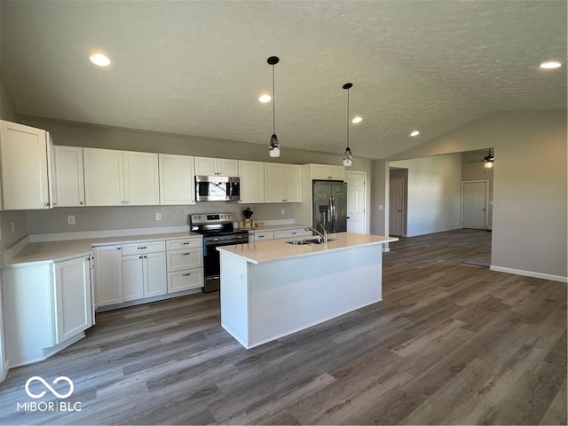 kitchen with white cabinets, decorative light fixtures, a center island with sink, and appliances with stainless steel finishes