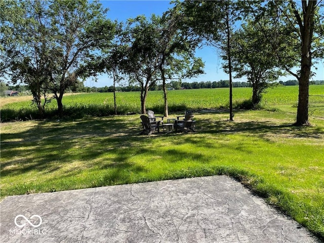 view of home's community featuring a lawn, a rural view, and a patio