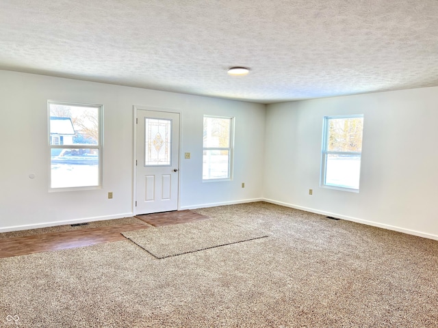 carpeted foyer featuring a textured ceiling