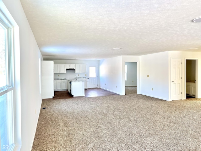 unfurnished living room featuring a textured ceiling and carpet