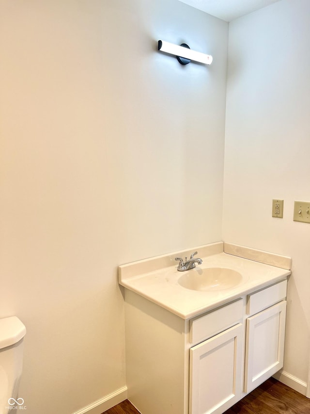 bathroom with toilet, hardwood / wood-style flooring, and vanity