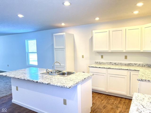 kitchen featuring sink, white cabinetry, light stone counters, a center island with sink, and dark wood-type flooring