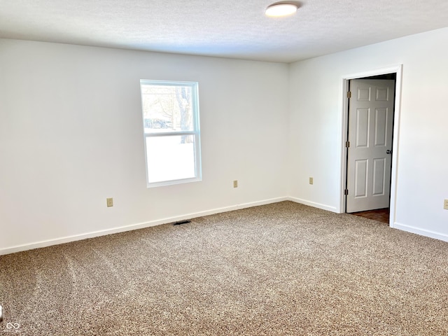 spare room featuring a textured ceiling and carpet