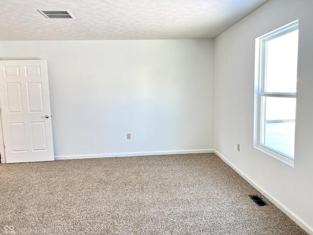 carpeted empty room featuring a textured ceiling