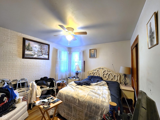 bedroom with ceiling fan, brick wall, and hardwood / wood-style flooring