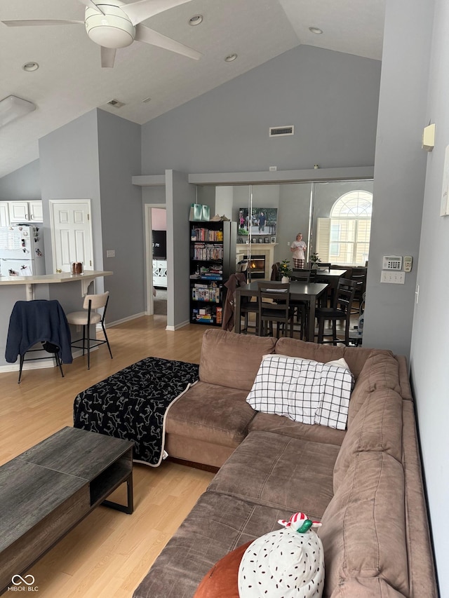 living room featuring light wood-type flooring, high vaulted ceiling, and ceiling fan