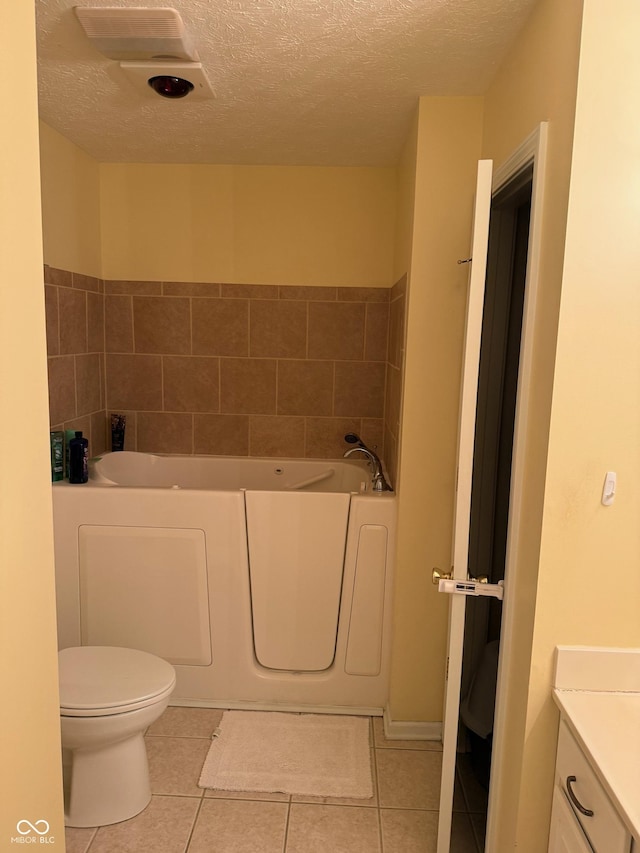 bathroom with a washtub, tile patterned flooring, a textured ceiling, toilet, and vanity