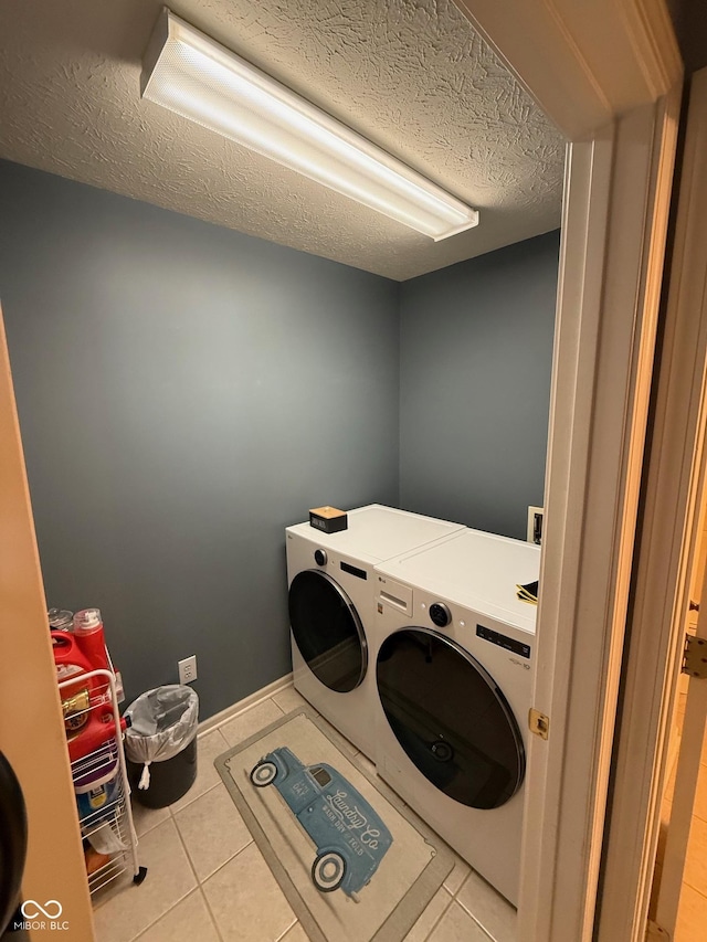 laundry area featuring separate washer and dryer, a textured ceiling, and light tile patterned floors