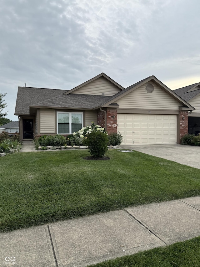 1294 Lexington Trl, Greenfield, IN 46140 - ranch-style home with an attached garage, concrete driveway, a front yard, brick siding, and a shingled roof