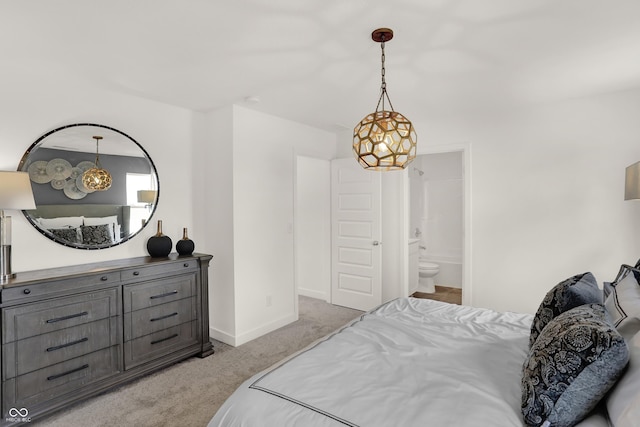 bedroom featuring baseboards, ensuite bathroom, and light colored carpet