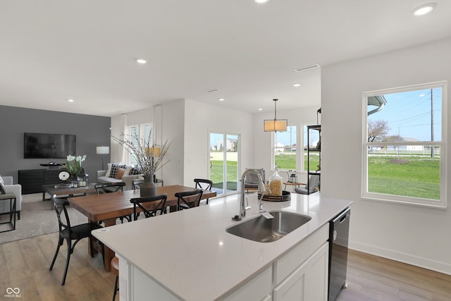 kitchen with light wood finished floors, recessed lighting, open floor plan, a sink, and dishwashing machine