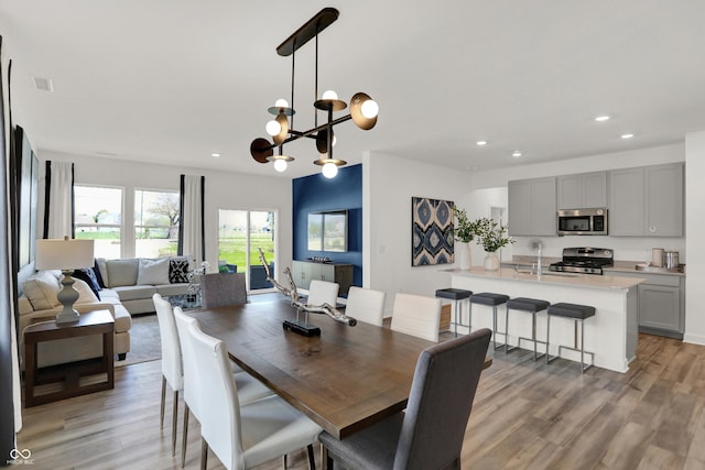 dining area with visible vents, a notable chandelier, light wood-style flooring, and recessed lighting