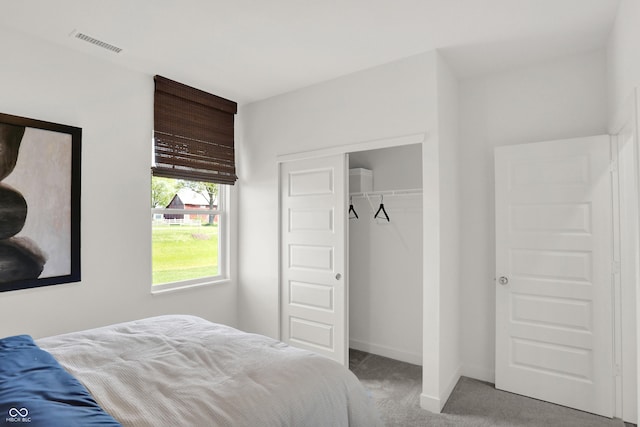 carpeted bedroom with a closet, visible vents, and baseboards