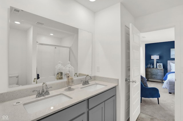 bathroom with double vanity, an enclosed shower, a sink, and ensuite bathroom