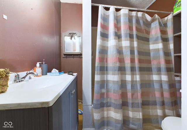 bathroom featuring a textured ceiling, toilet, and vanity