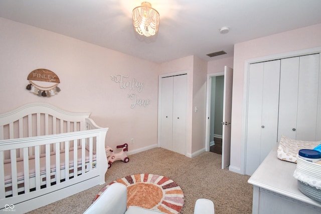 bedroom featuring light colored carpet, a nursery area, and multiple closets