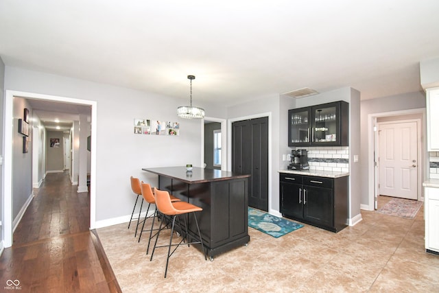 kitchen featuring a kitchen bar, a chandelier, a kitchen island, pendant lighting, and backsplash