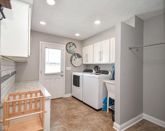 clothes washing area featuring cabinets, light tile patterned flooring, and washing machine and clothes dryer