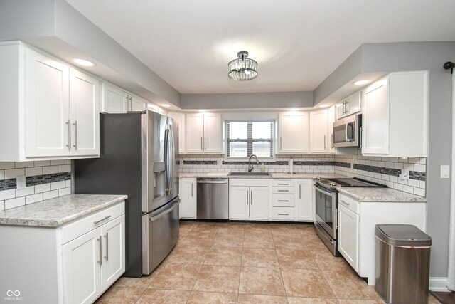 kitchen with tasteful backsplash, sink, white cabinets, and appliances with stainless steel finishes