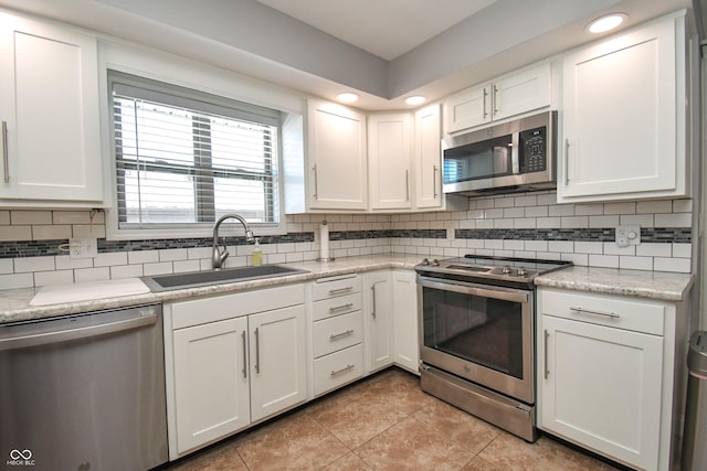 kitchen with light tile patterned flooring, sink, appliances with stainless steel finishes, white cabinets, and backsplash