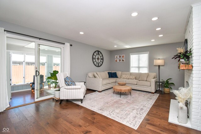 living room with a brick fireplace and dark hardwood / wood-style floors