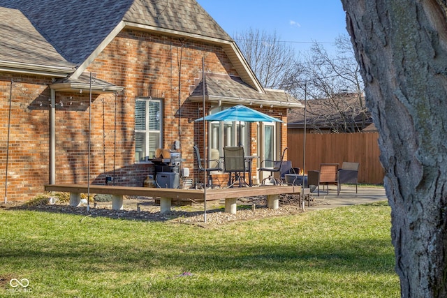 back of house featuring a wooden deck, a patio area, and a lawn