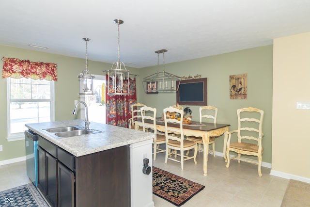 kitchen featuring sink, stainless steel dishwasher, a kitchen island with sink, and hanging light fixtures