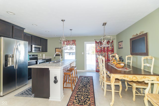 kitchen with a center island with sink, a breakfast bar area, appliances with stainless steel finishes, hanging light fixtures, and sink