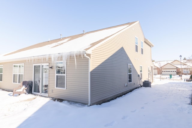 snow covered house featuring cooling unit