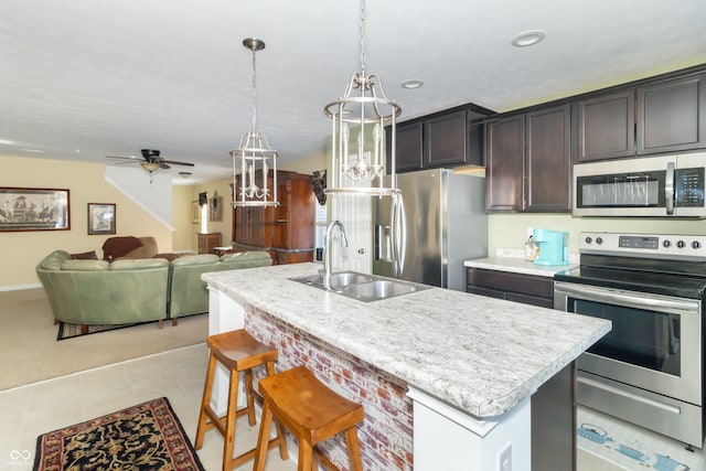 kitchen featuring stainless steel appliances, sink, ceiling fan, a center island with sink, and pendant lighting