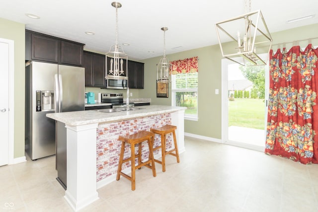1226 Arlington Dr, Greenfield, IN 46140 - kitchen with stainless steel appliances, light countertops, a center island with sink, a breakfast bar, and hanging light fixtures