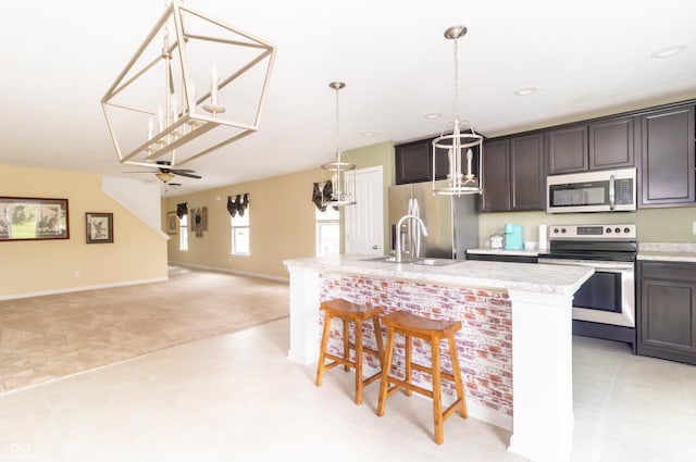 1226 Arlington Dr, Greenfield, IN 46140 - kitchen with appliances with stainless steel finishes, a kitchen bar, hanging light fixtures, an island with sink, and dark brown cabinetry