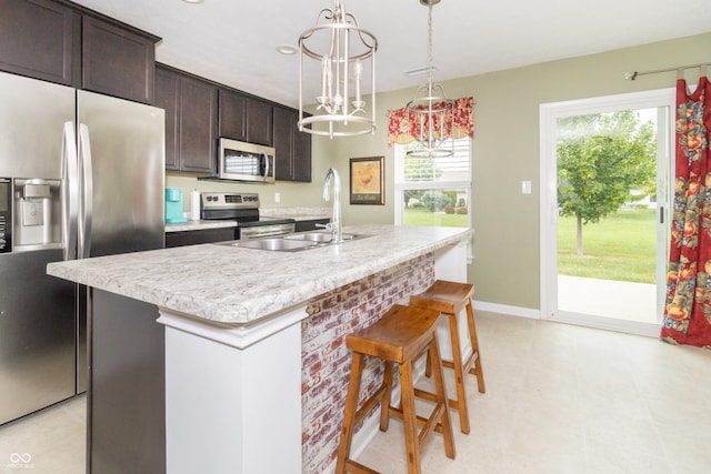 1226 Arlington Dr, Greenfield, IN 46140 - kitchen with appliances with stainless steel finishes, light countertops, a center island with sink, a kitchen breakfast bar, and dark brown cabinets